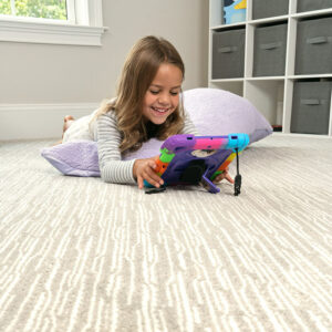 Kid laying on carpet playing on tablet